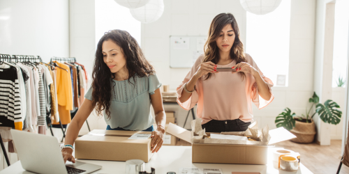 Two women packaging clothes orders for their business